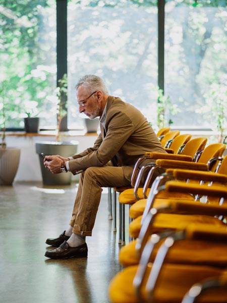 A gentleman on his phone sitting in a waiting room